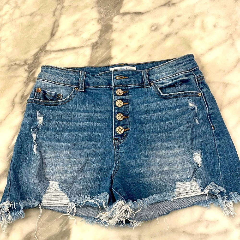 Enjean distressed, button-fly, frayed hem jean shorts in medium blue rinse.